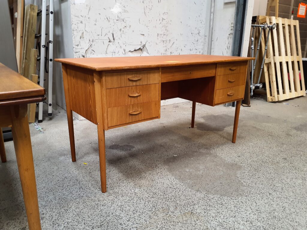 Fritstående skrivebord i teak med skuffer foran og lang hylde bagved
