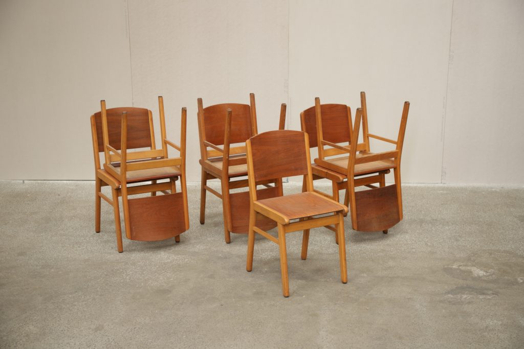 Mid-century modern wooden chairs with reddish-brown upholstered seats for dining.