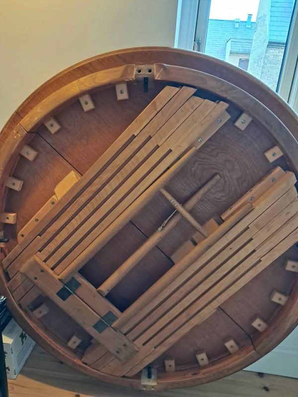 Midcentury modern circular folding table with intricate wooden mechanism.