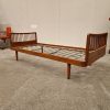 Mid-century modern wooden daybed with slat headboards, stylish furniture.