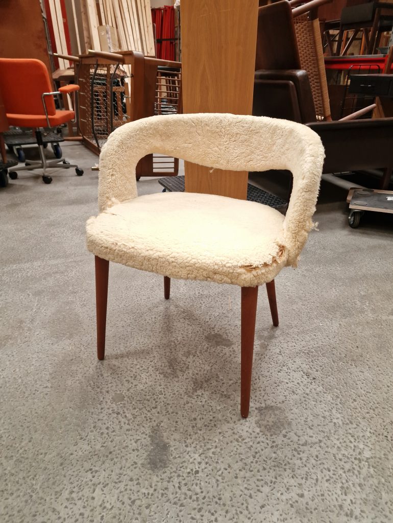 Worn beige armchair with unique cutout back.