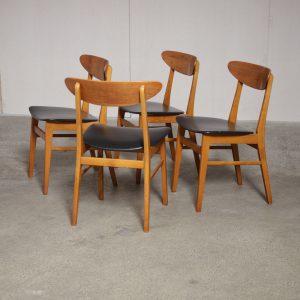 Vintage mid-century dining chairs with light wood frames and black upholstered seats.