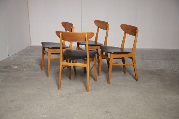 Vintage mid-century dining chairs with light wood frames and black upholstered seats.